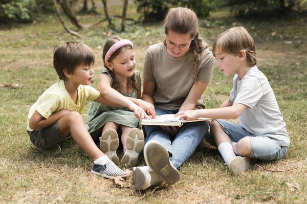 insegnante-del-colpo-pieno-e-bambini-che-tengono-libro (1)
